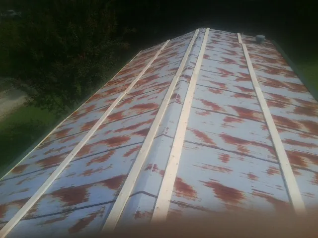 Rusted metal roof panels with new wood purlins before replacement — Storm Damage Roof Repair in West Granby by Roofing Brothers