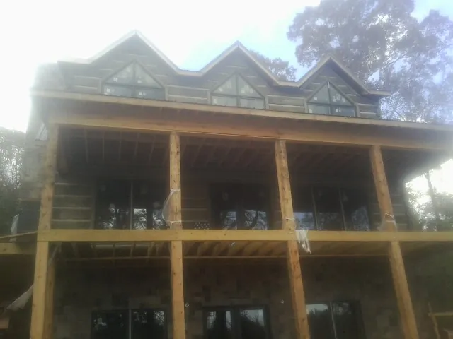Dormers and porch framing on a large log home under construction — Roof Coating work by our crew in West Granby