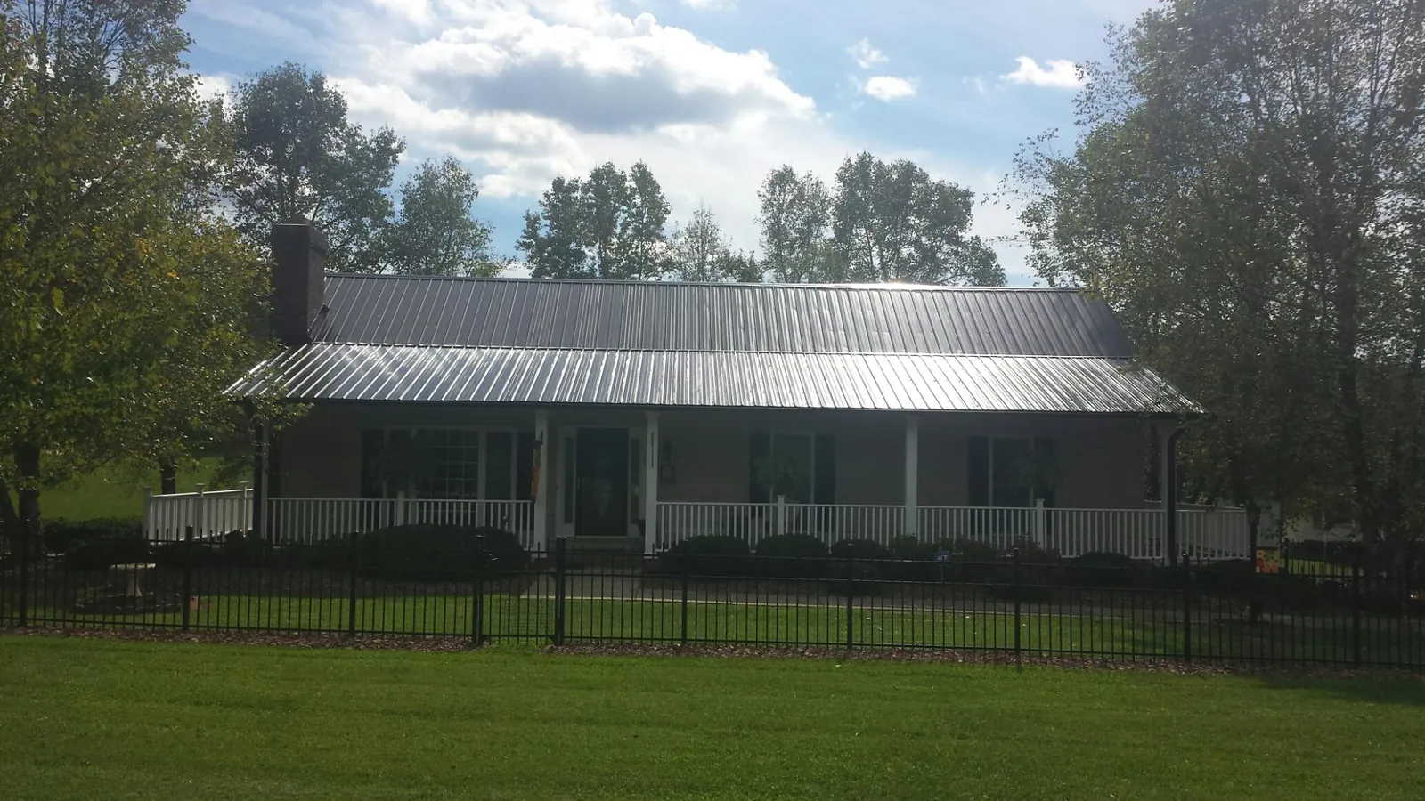 Gray metal roof on a brick ranch with a full width front porch — Gutter Guard Installation work by our crew in West Granby