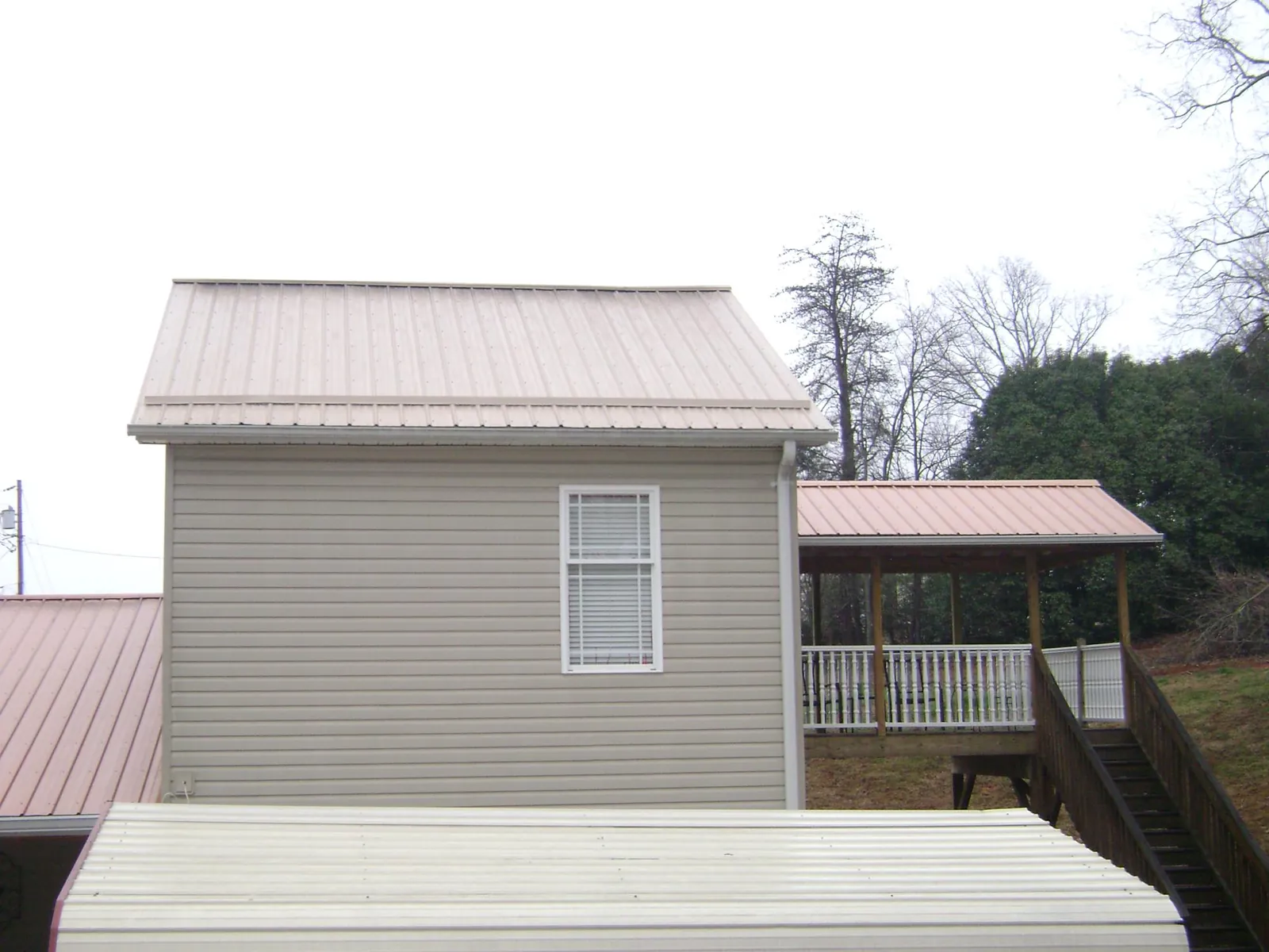 Tan metal roofs on a two story addition and attached porch, from a Roof Replacement job in West Granby