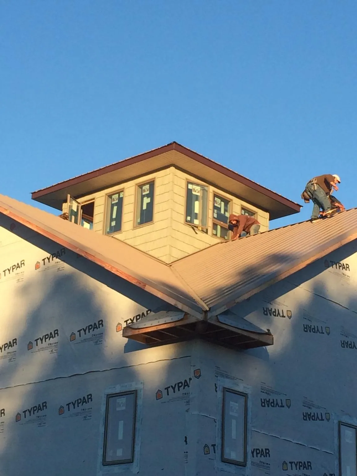 Roofers working around a rooftop cupola on a new metal roof at sunset — Roof Waterproofing in West Granby by Roofing Brothers